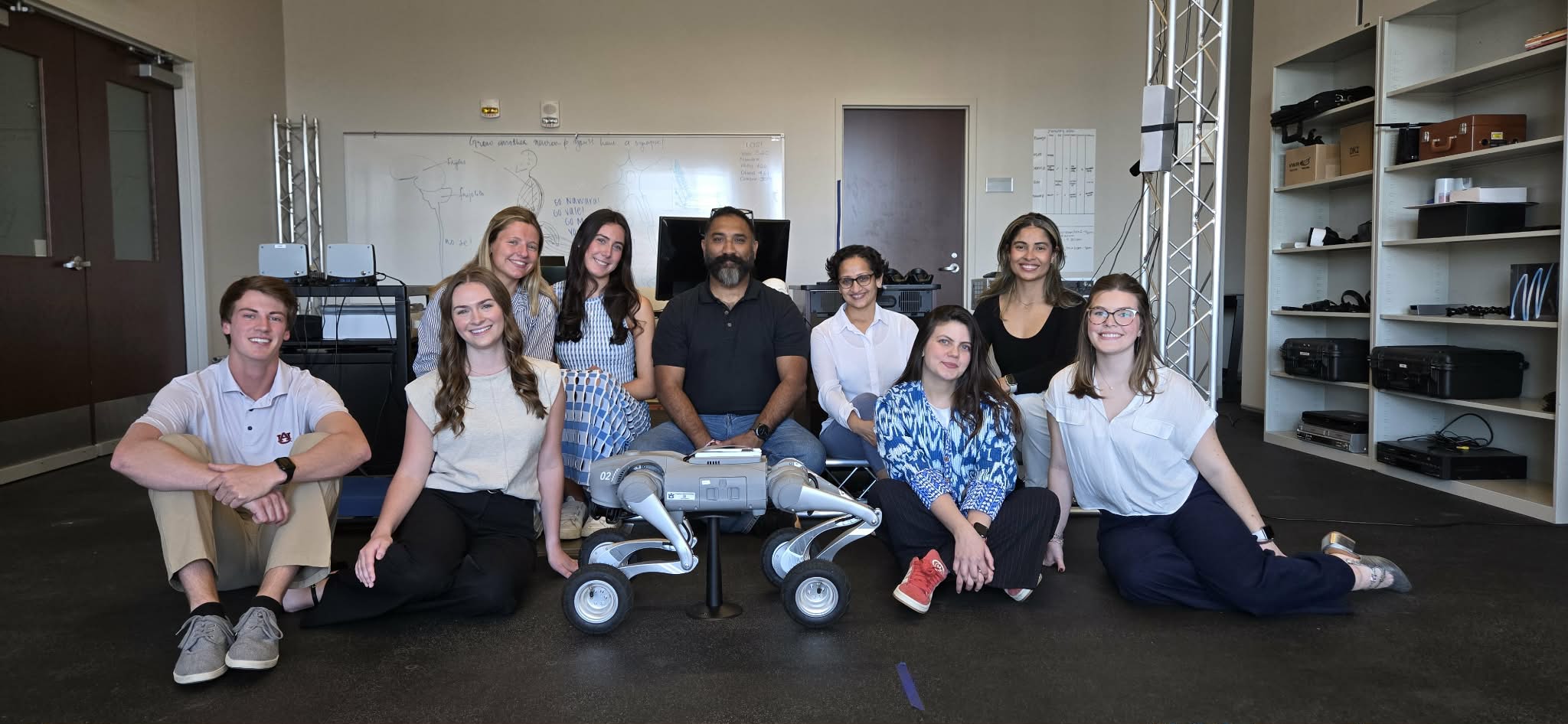 Seven students in the Sensorimotor and Movement Control Lab pose for a picture with Circuit, the Robotic Dog. Lab directors Harsimran Baweja and Niyati Shah are pictured in the center.
