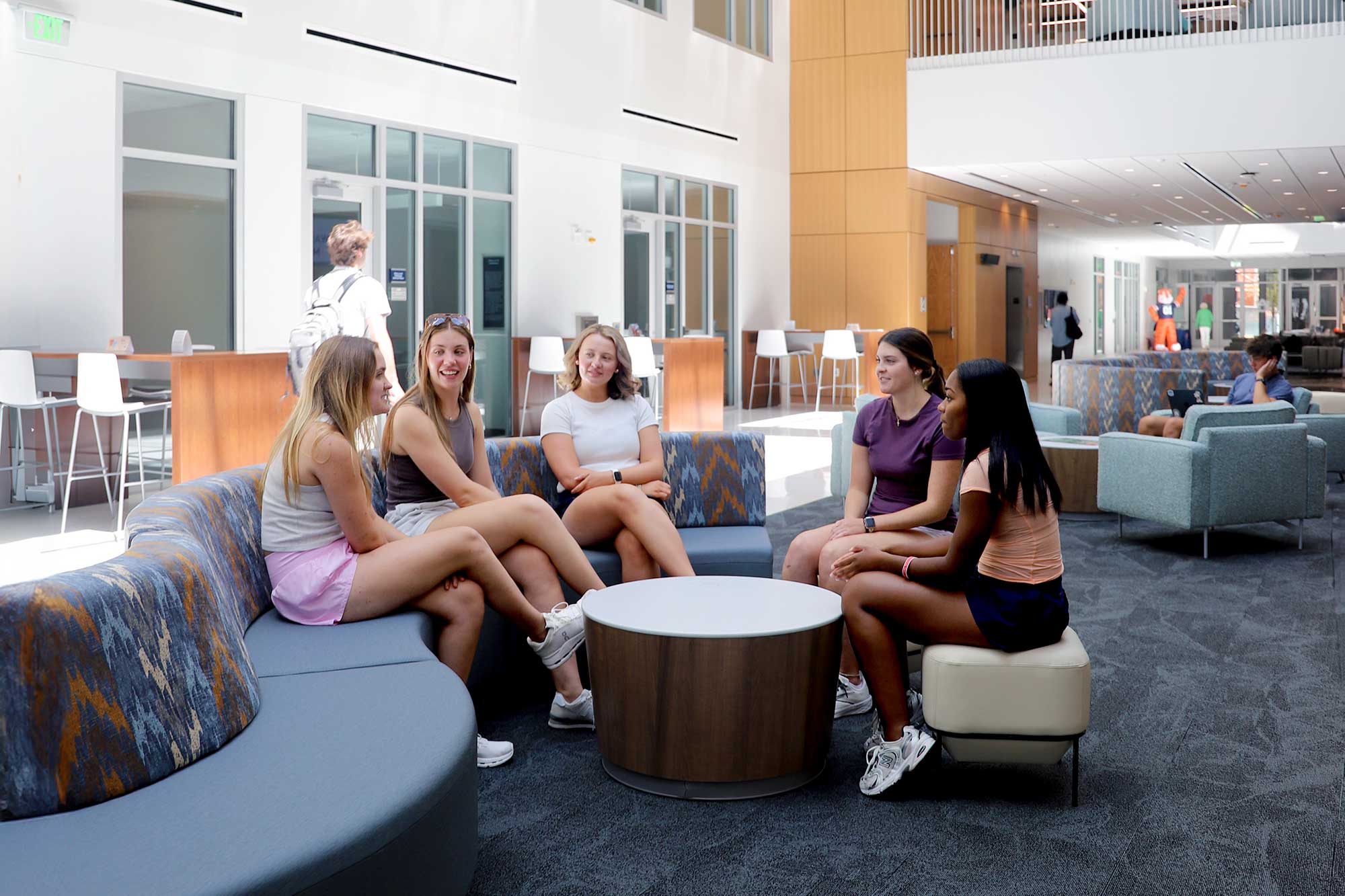 four girls sit in the commons of the college of education building.