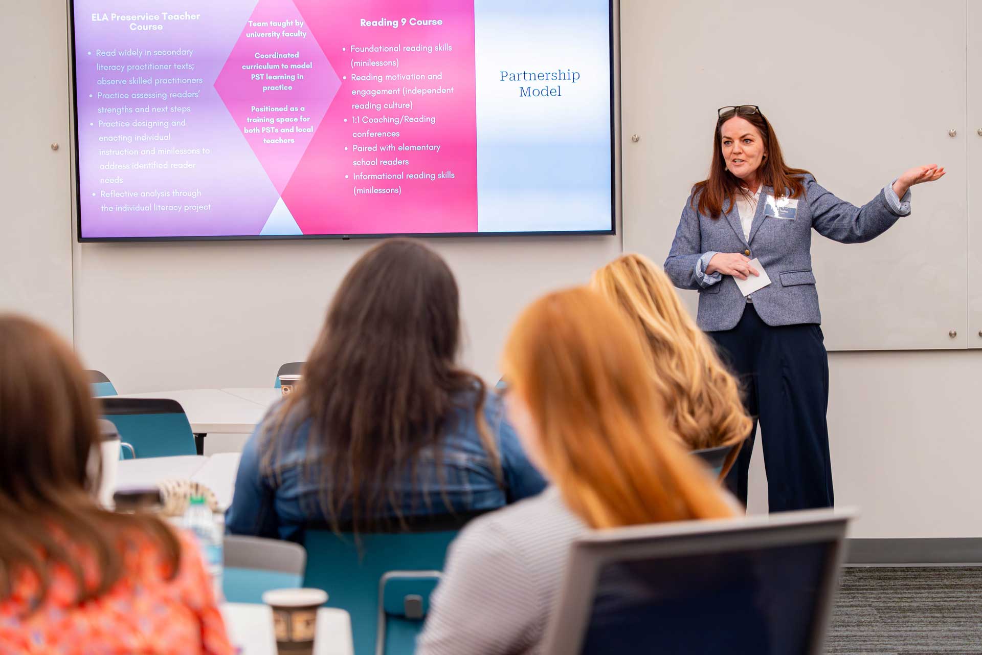 A woman leads a presentation next to a powerpoint at the Education Summit.