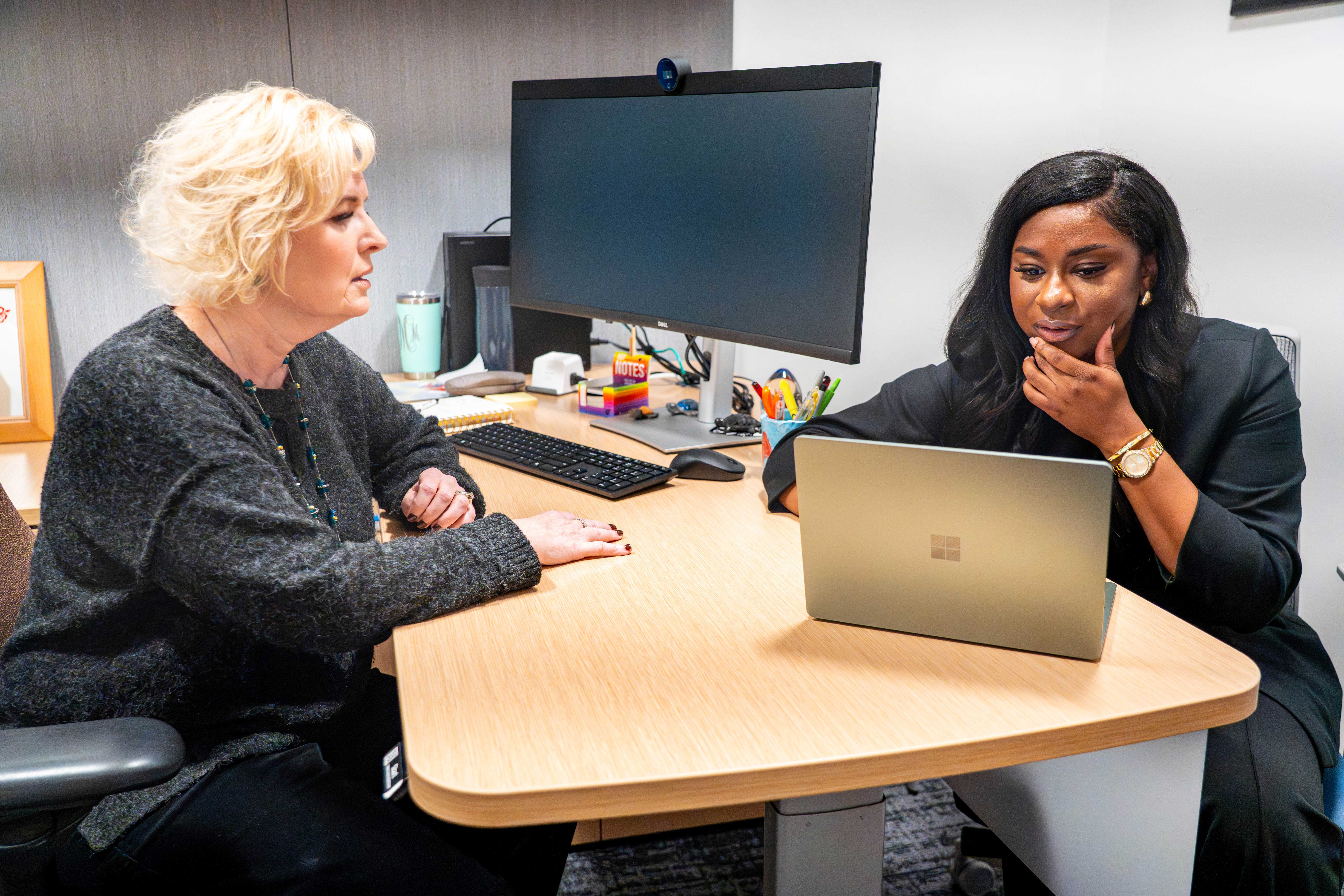 A student and professor work together in an office on a laptop.