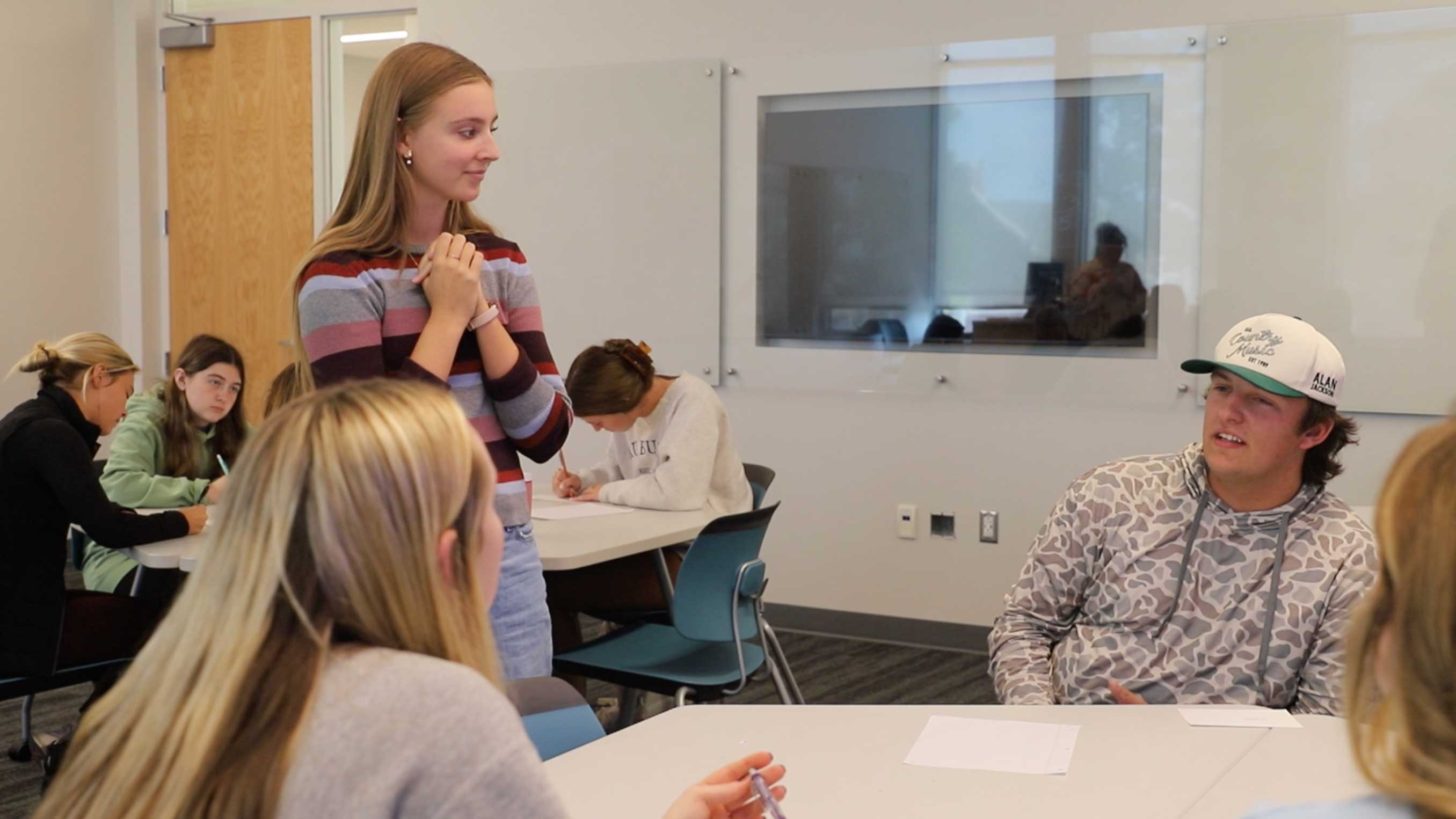 A student meets with her learning community at a table in a classroom.