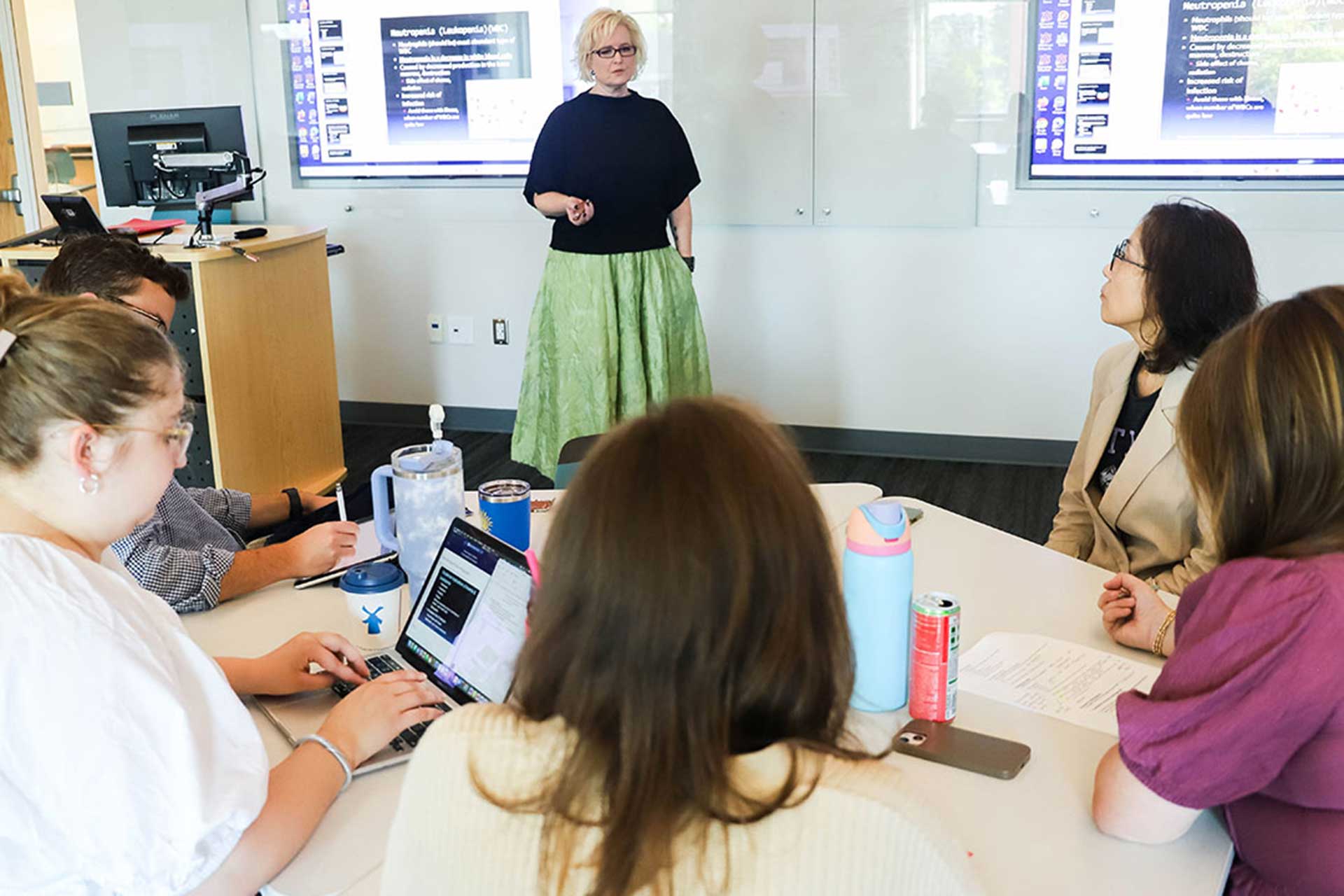 Dr. Meyer works with students in a classroom.