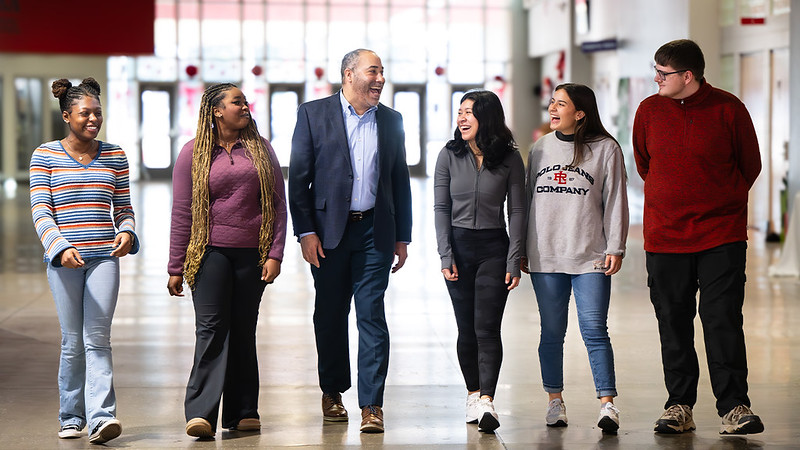 A college of education faculty member walks with students in opelika high school.