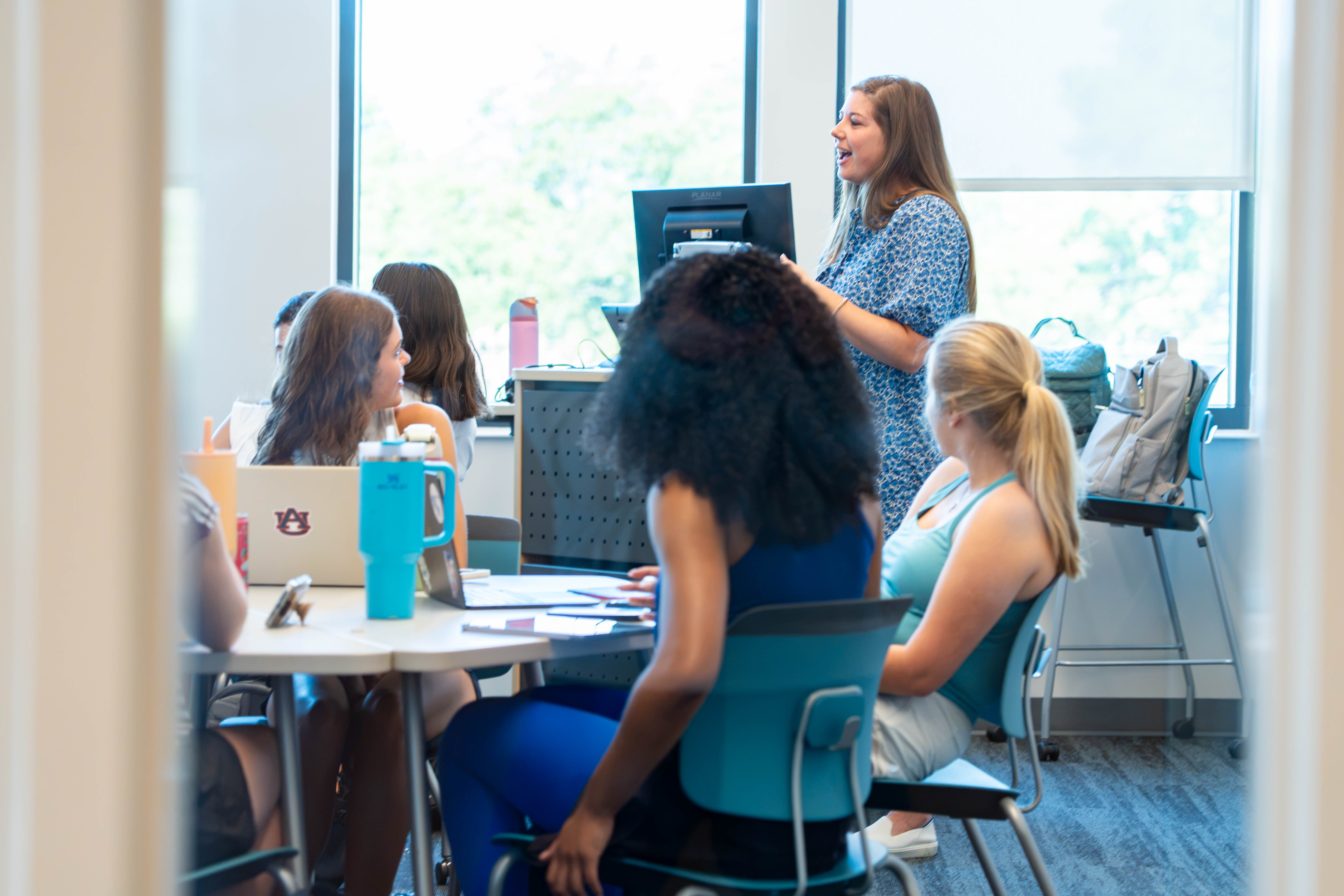 A student presents to her classmates in a classroom.