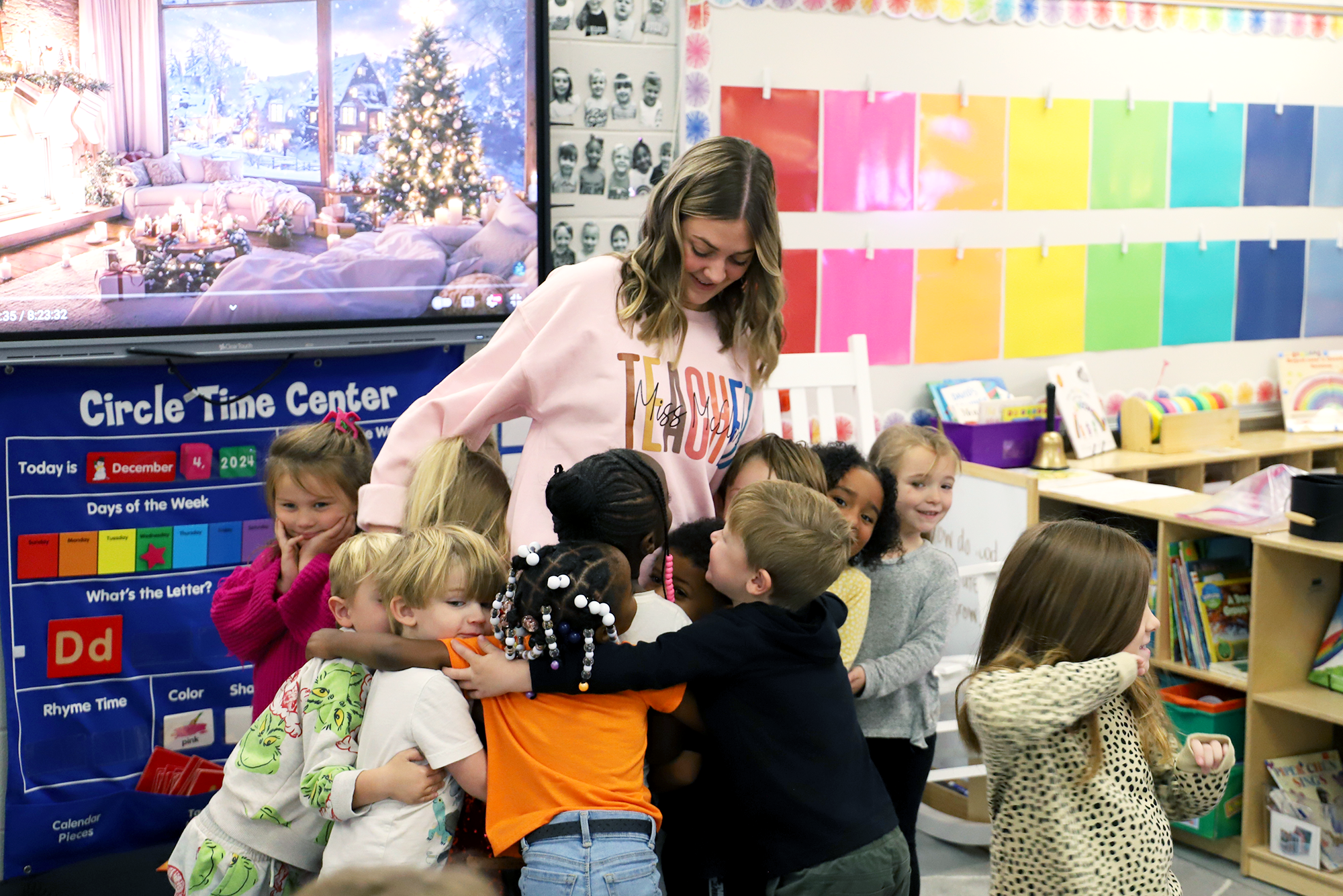 A student teacher hugs her students