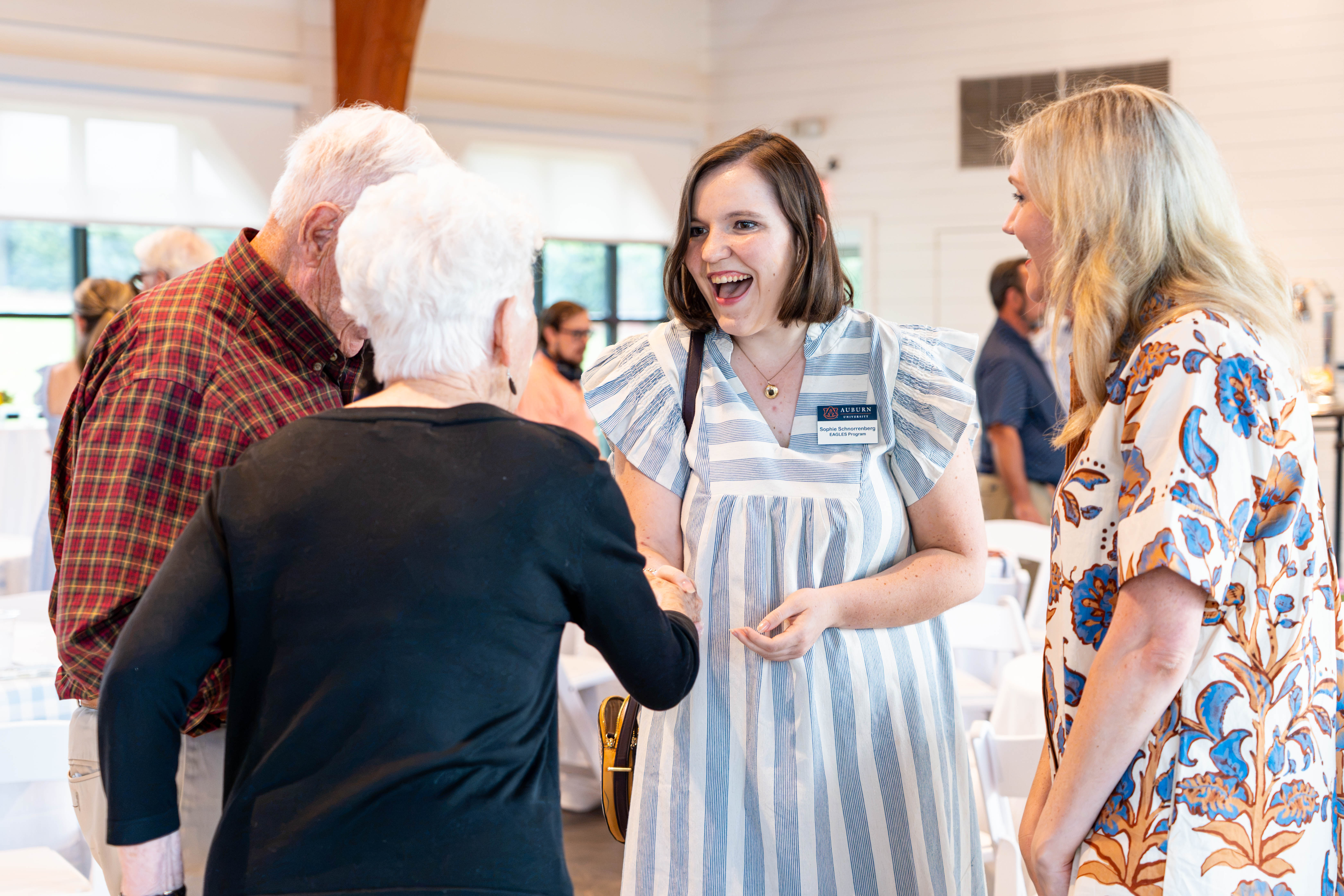 an eagles student shaking hands with guests at the red barn event.