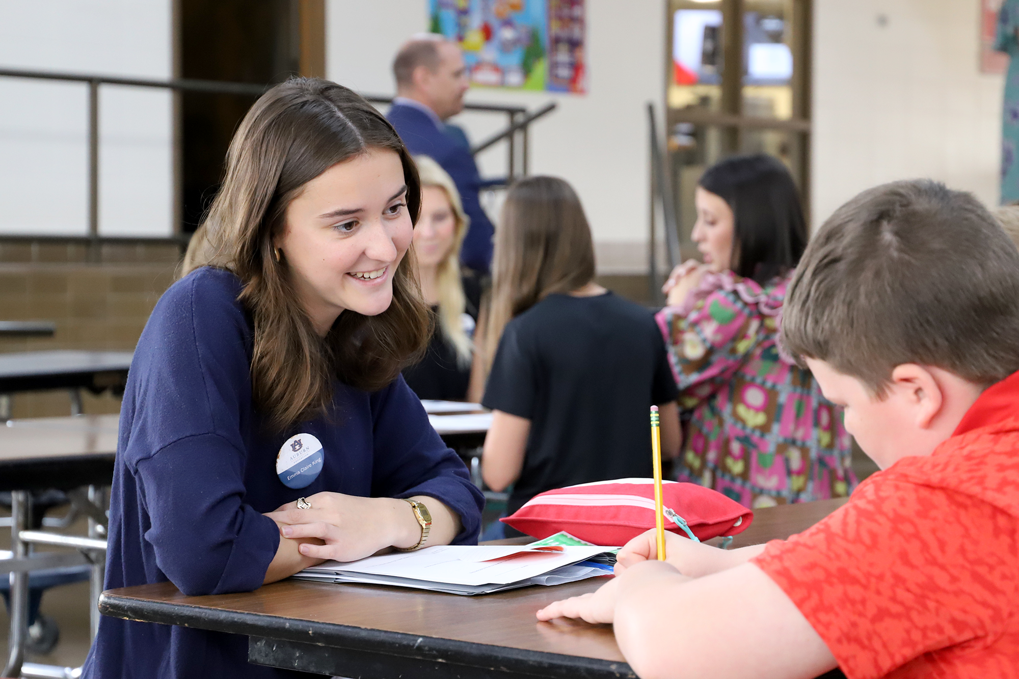 A student teacher works with a student at their desk