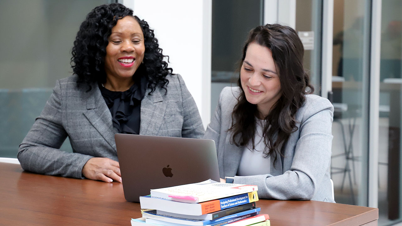 A student works with her professor at a table