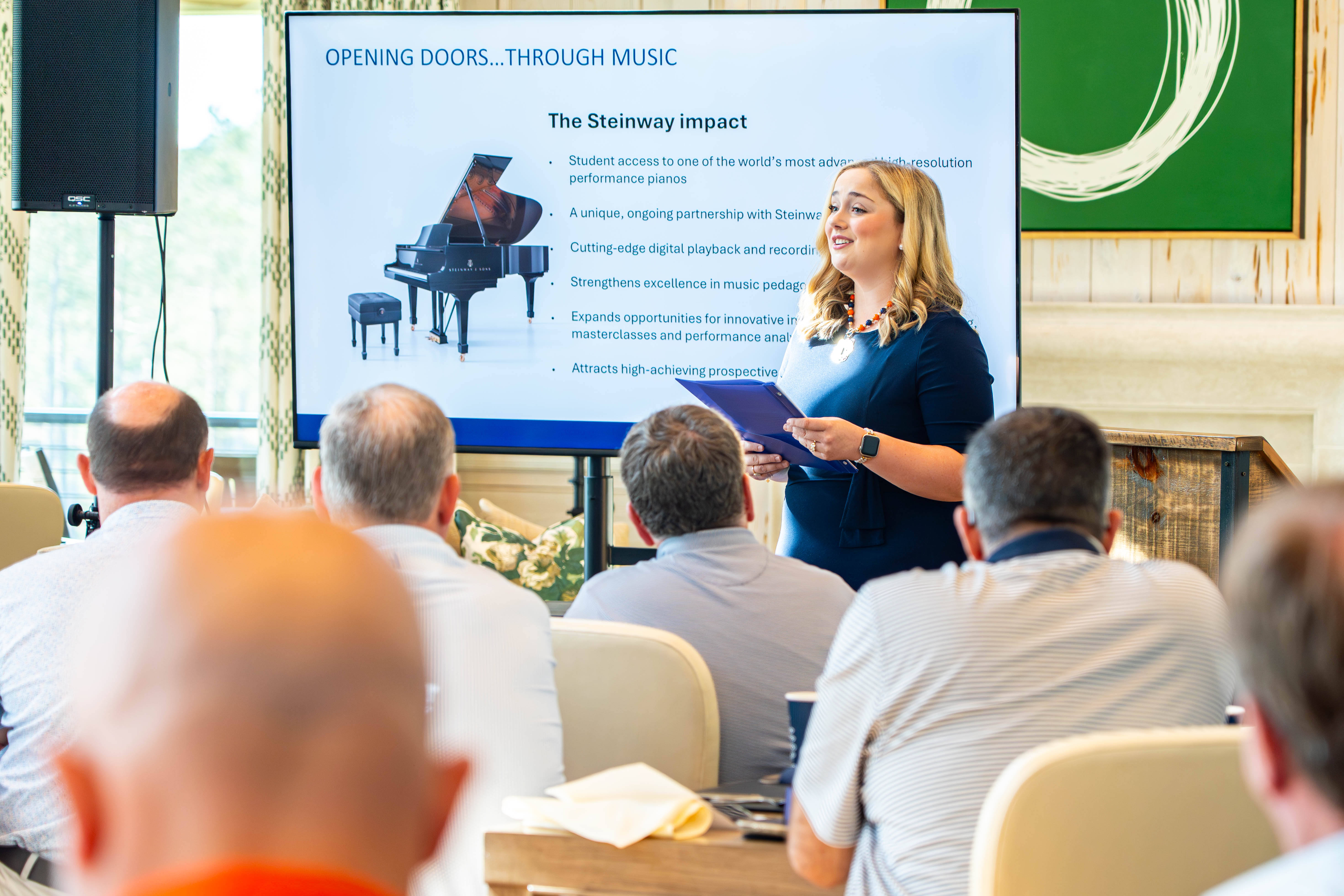 A woman gives a presentation about the impact of Steinway pianos.