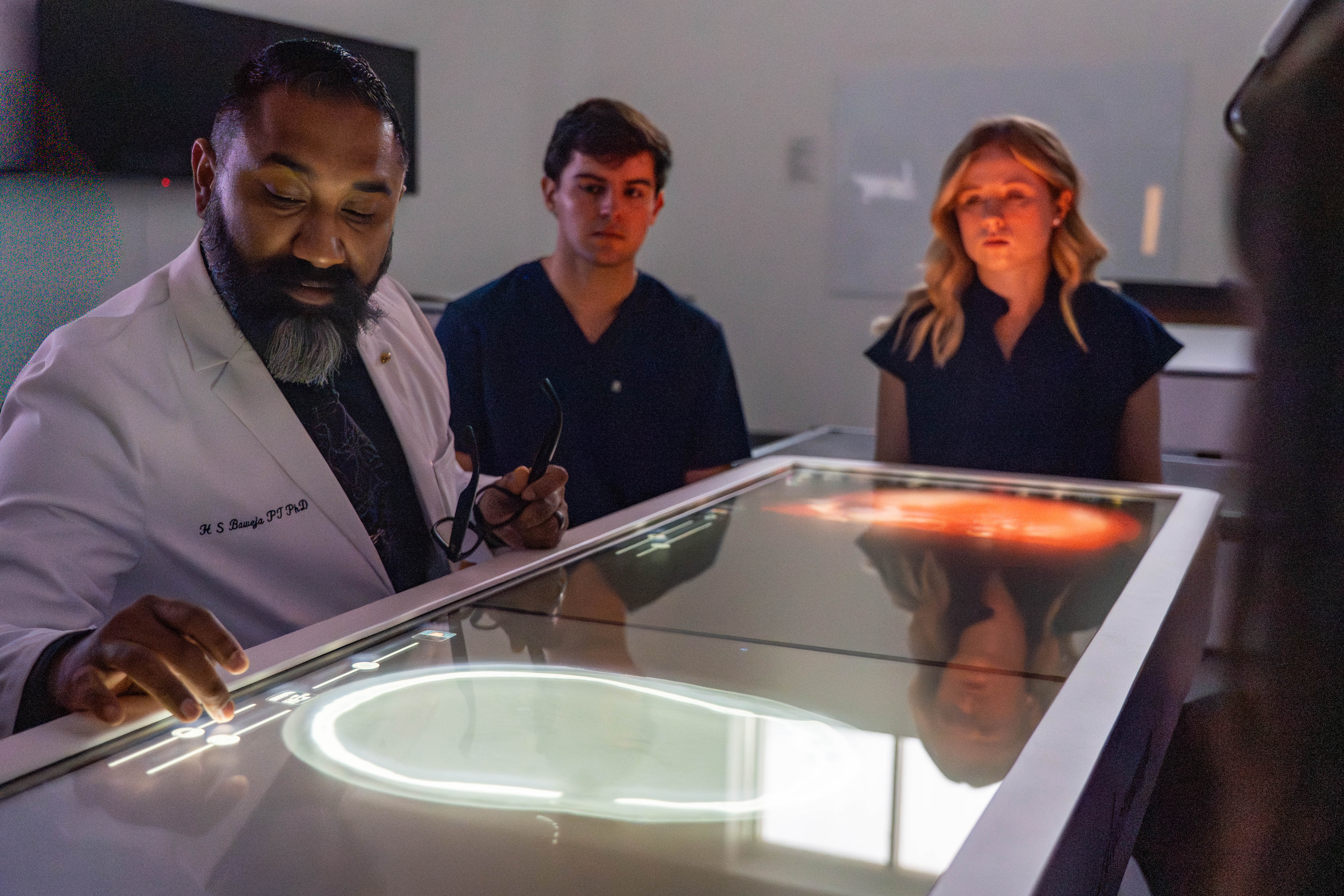 Dr. Baweja works with students at a digital anatomy table. 