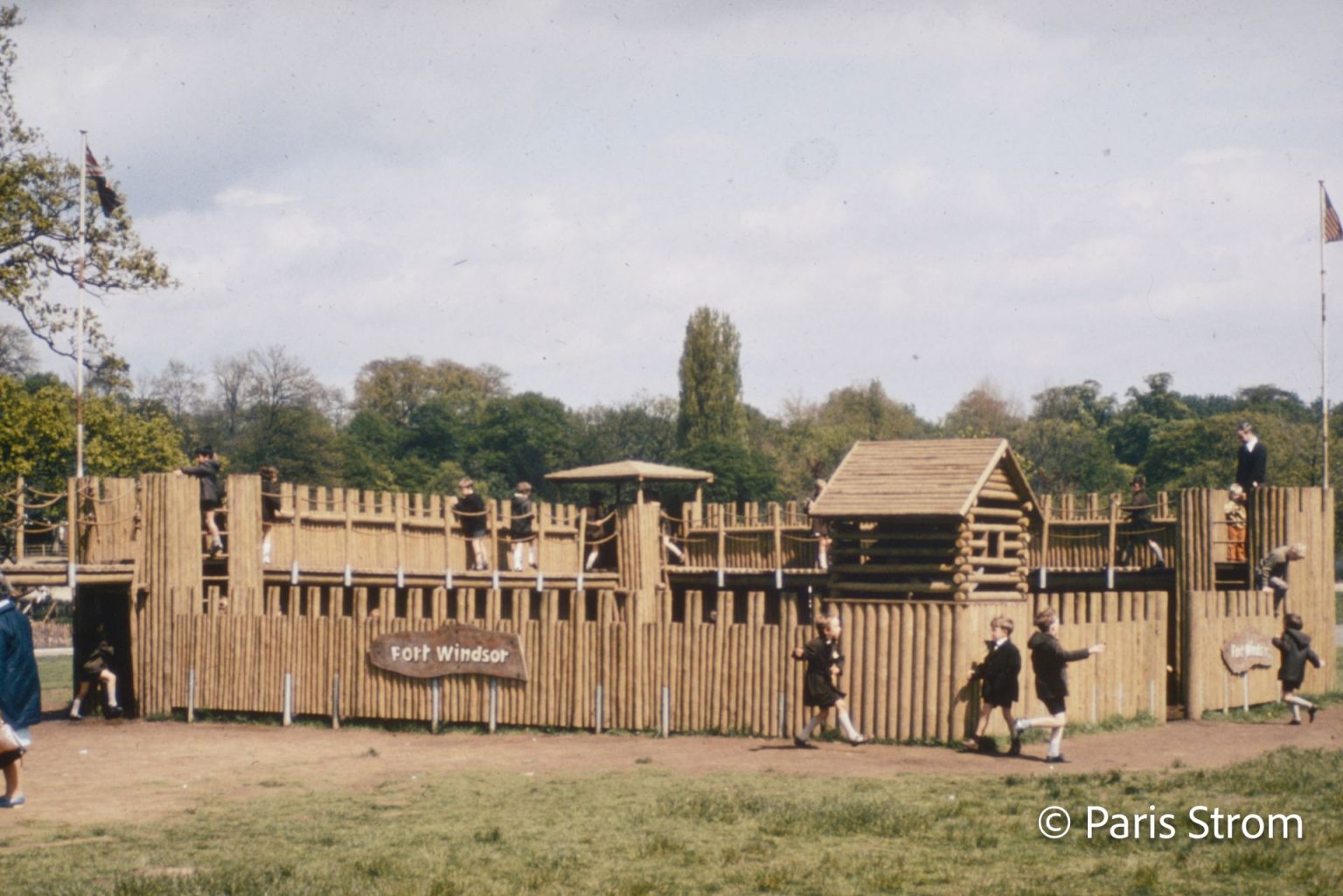 Uniformed school boys play among a log structure build to resemble a fort.