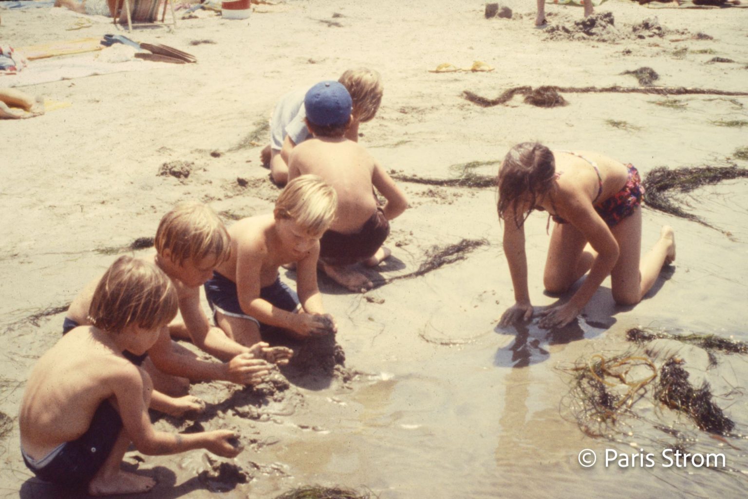 Young boys play in the sand at the beach.