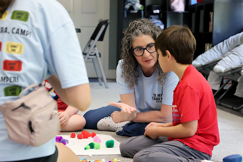A teacher working with a young student on the floor